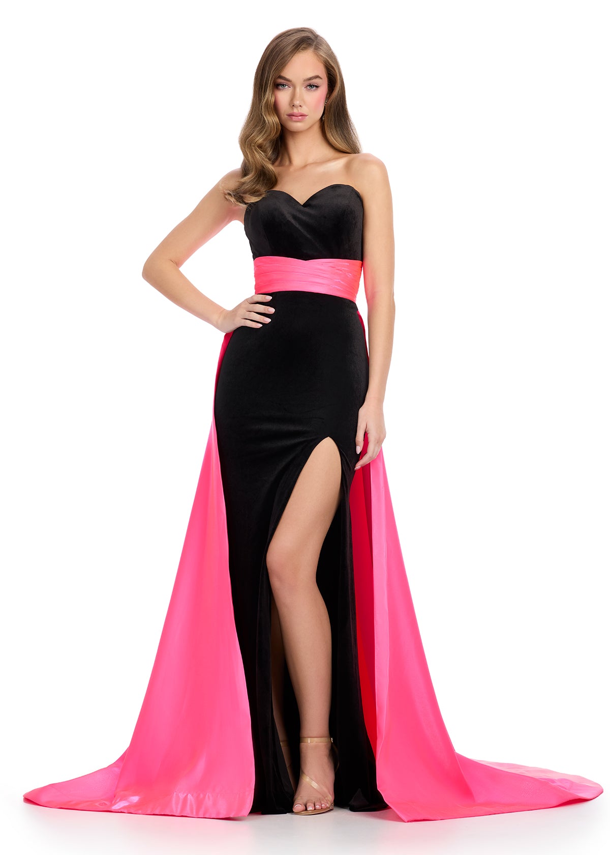 Classic and elegant strapless velvet gown featuring a figure-flattering satin overskirt that cinches the waist, paired with a left leg slit for a sophisticated and timeless look. Perfect for special occasions.