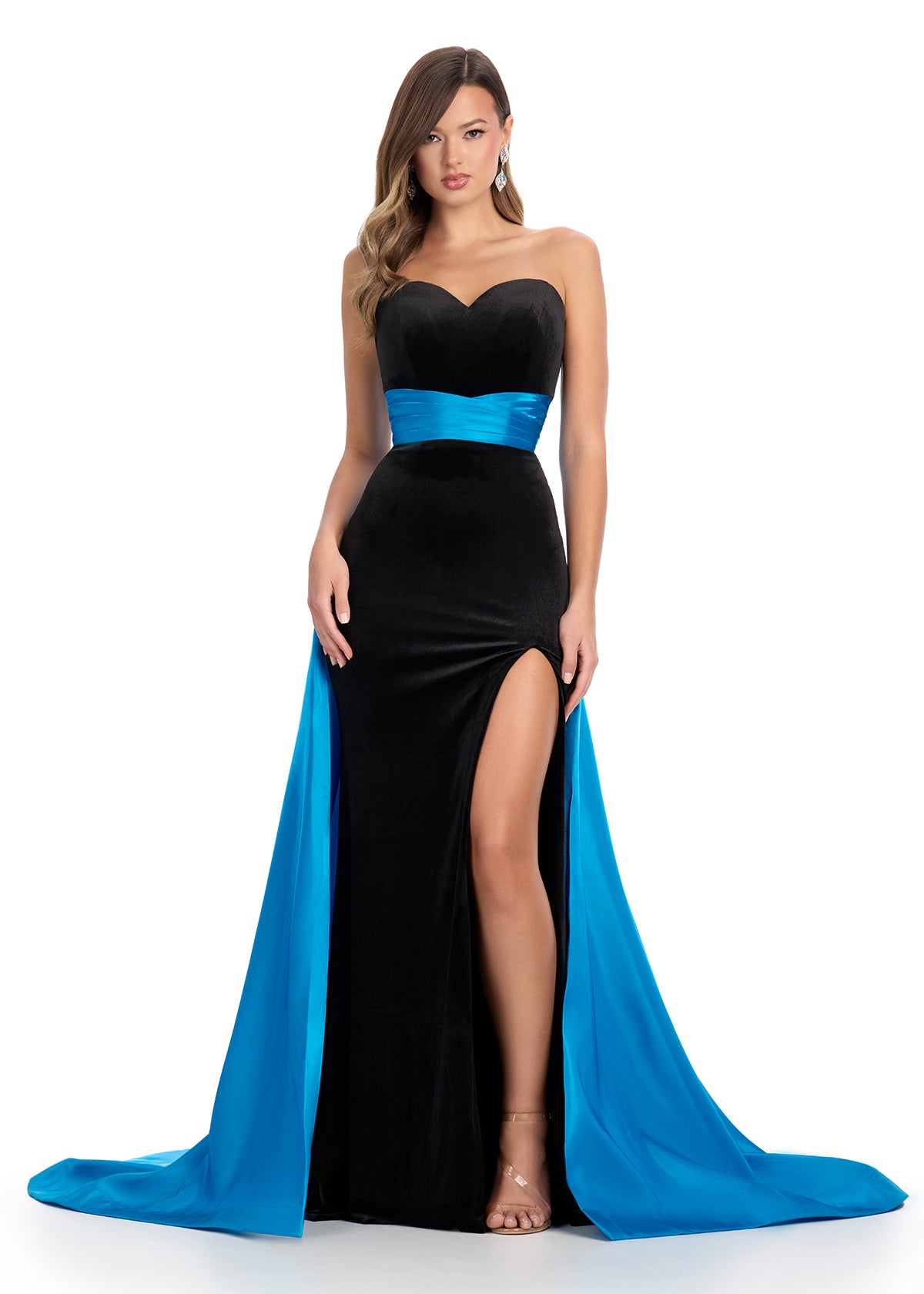 Classic and elegant strapless velvet gown featuring a figure-flattering satin overskirt that cinches the waist, paired with a left leg slit for a sophisticated and timeless look. Perfect for special occasions.