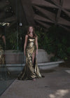 Video - Sleek and glamorous one-shoulder metallic jersey gown featuring a wrap skirt, left leg slit, and a sweep train for a bold and sophisticated look. Perfect for making a statement at any special occasion.